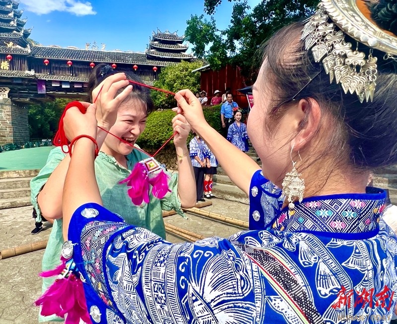 9月30日,通道侗族自治县坪坦乡皇都侗文化村,侗族姑娘给游客戴上侗家